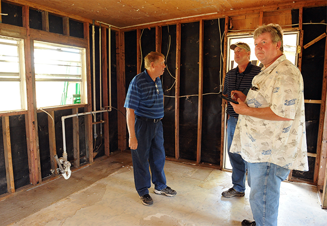 FEMA Inspectors and residents surveying a home damaged during a flood.