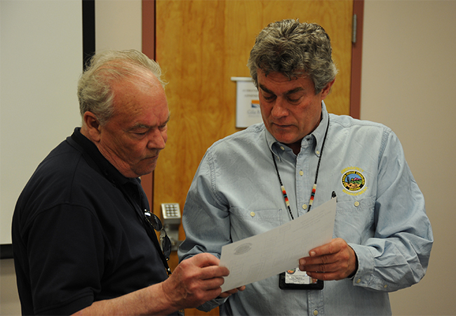 Deputy Public Assistance group supervisor reviews a list of recovery projects with an Emergency Operations coordinator for the Gila River Indian Community.