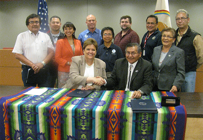 A group of FEMA representatives and Navajo Nation members together at a table after signing FEMA-Tribe Agreement.