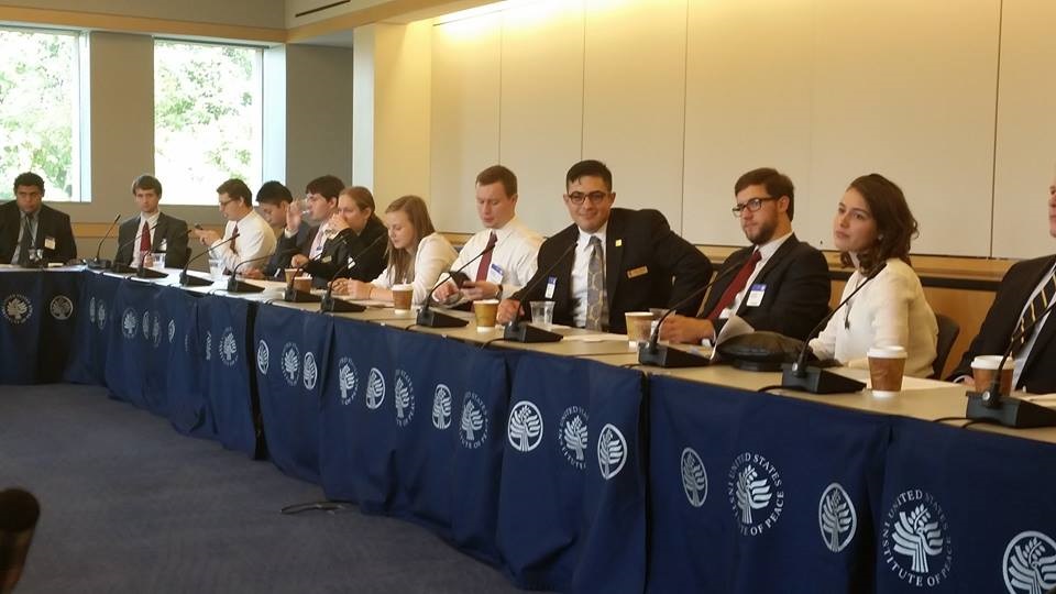 A diverse group of people sitting at a large, wrap around table