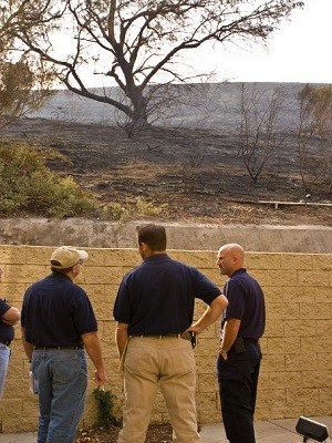 Federal Coordinating Officer and Operations Section Chief discuss funding eligibility in front of an area burned by the recent wildfires in Anaheim, California.