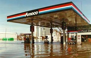 Exterior photo of a gas station, surrounded by floodwaters several feet deep