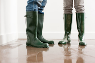 Two people with boots on standing on a wet floor.
