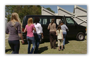 It appears one person is leading the others into a van. The van does not have any markings that link it to a specific government or NGO. 