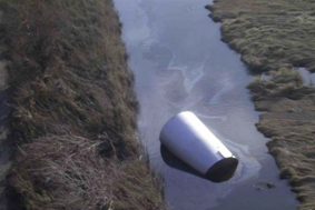 Oil drum left in a ditch of water